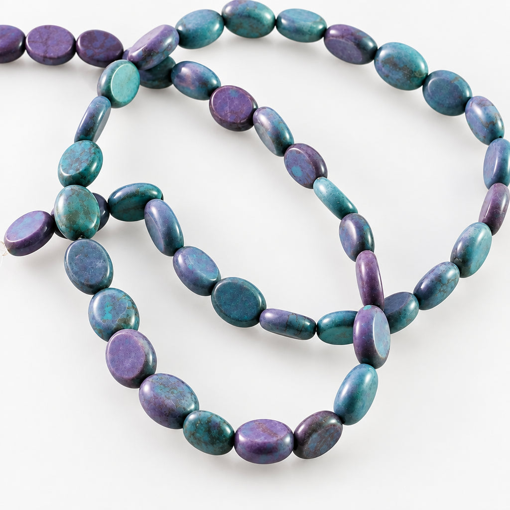 A strand of polished irregular oval beads in a dark blue-gray color with natural marbling and metallic luster, arranged on a plain white background.