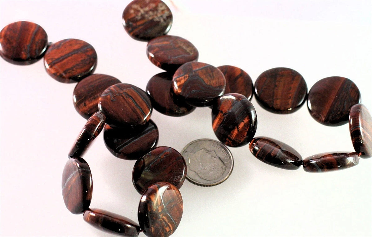 A strand of polished dark brown tiger's eye beads with natural banding, displayed on a white background with a silver coin for scale.