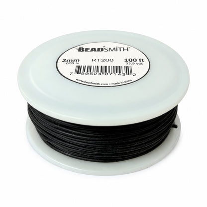 A close-up of a spool of black cord or thread with a white plastic rim and a circular product label on top. The label shows text including '2mm', 'RT200', and '100 ft', along with a barcode and the website beadsmith.
