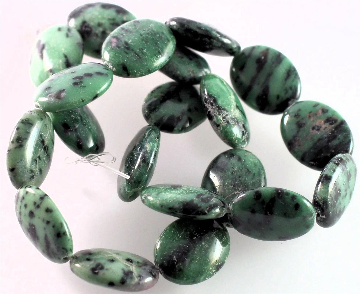 A strand of polished green jasper oval beads with dark brown and black mottled veining, displayed on a plain white background.