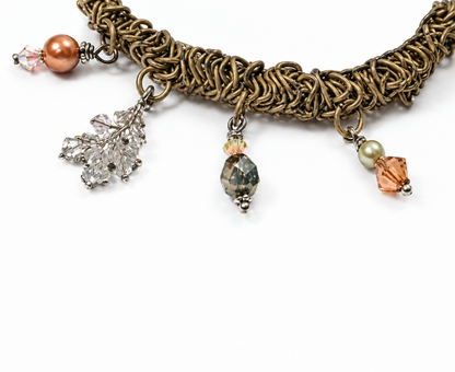 A close-up of a handmade braided cord bracelet or necklace with dangling charms, including a silver leaf, a small skull, and peach-colored beads, on a white background with the text '*Sample Usage' at the bottom.