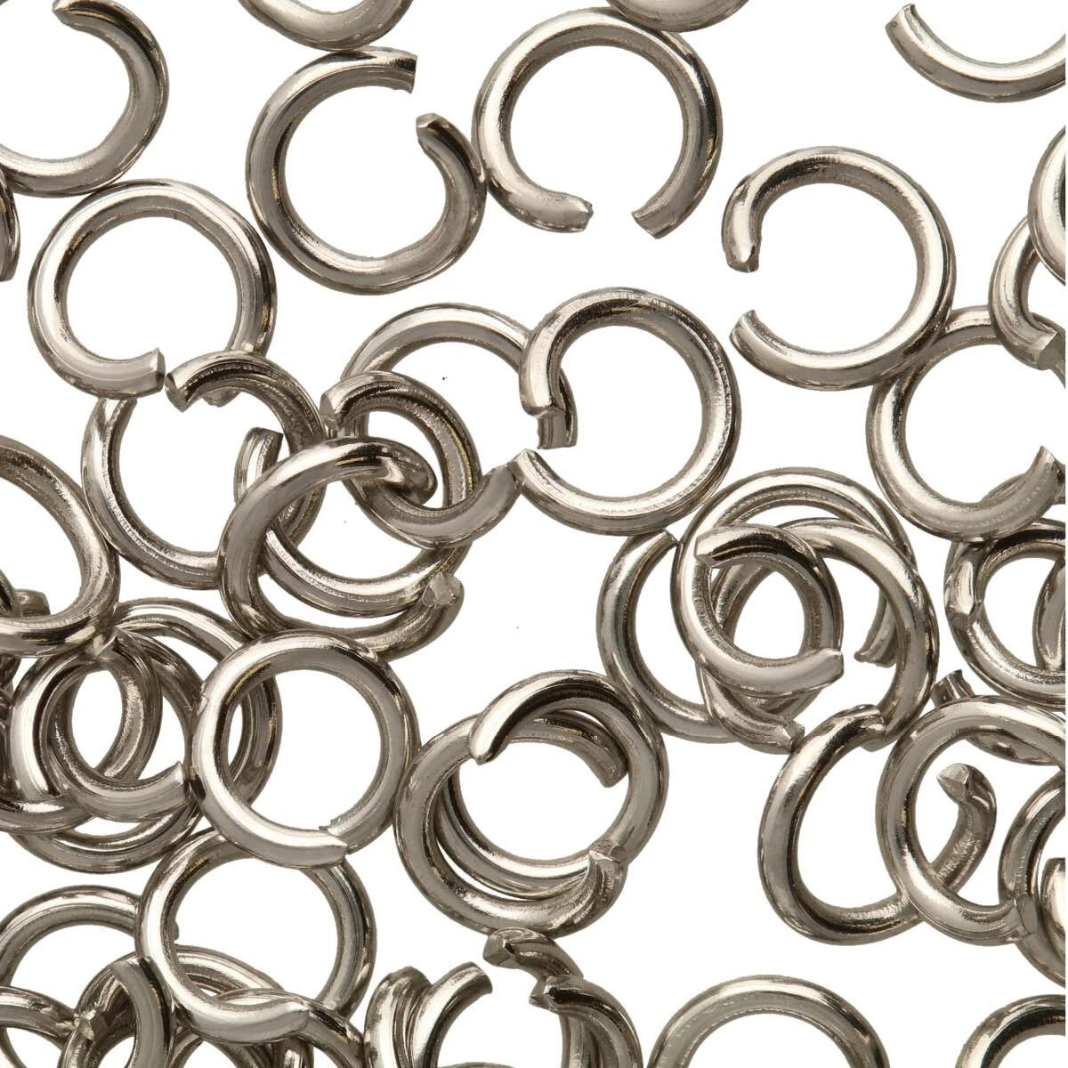 A pile of small silver metal jump rings with a split center, scattered on a plain white background.