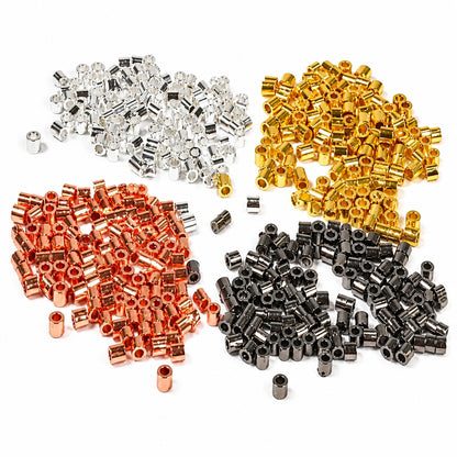 Four piles of small cylindrical bead spacers or seed beads in different metallic finishes: silver, gold, copper, and gunmetal gray, arranged on a plain white background.