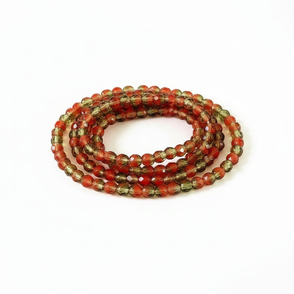 A coiled strand of faceted gemstone beads in alternating translucent red and smoky brown-green tones, photographed on a clean white background.