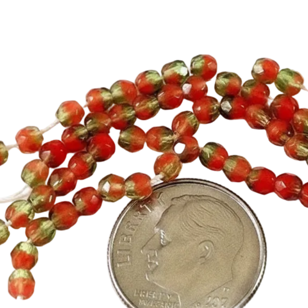 Red and green faceted glass beads on a white background with a US quarter coin for scale.