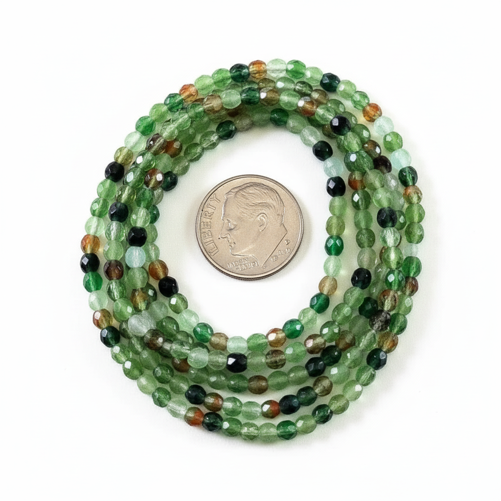 A coiled strand of faceted green gemstone beads with mixed earthy tones, shown next to a US dime for scale on a plain white background.