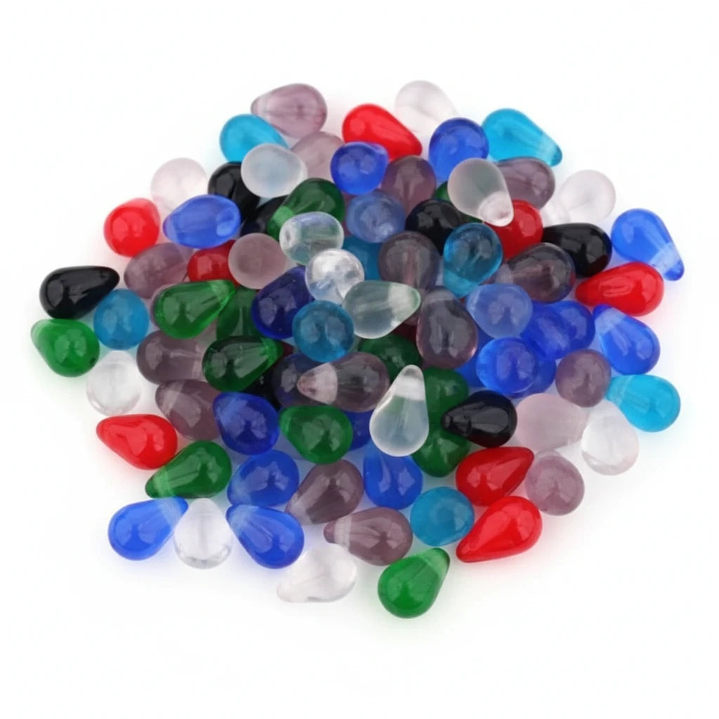 A close-up of many small teardrop-shaped beads in assorted translucent colors including blue, green, red, black, pink, purple, and clear on a white background.