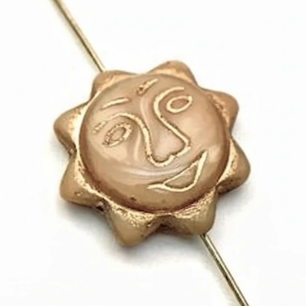 A single round sun-shaped bead with a carved face, finished in a warm metallic gold/bronze tone, threaded on a thin gold wire against a plain white background.
