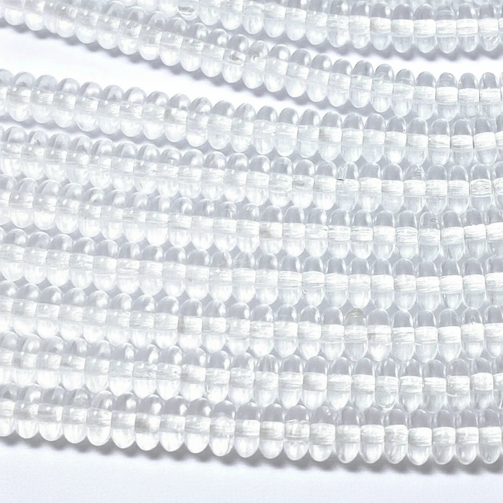 Clear round faceted beads strung in multiple rows on a white background.