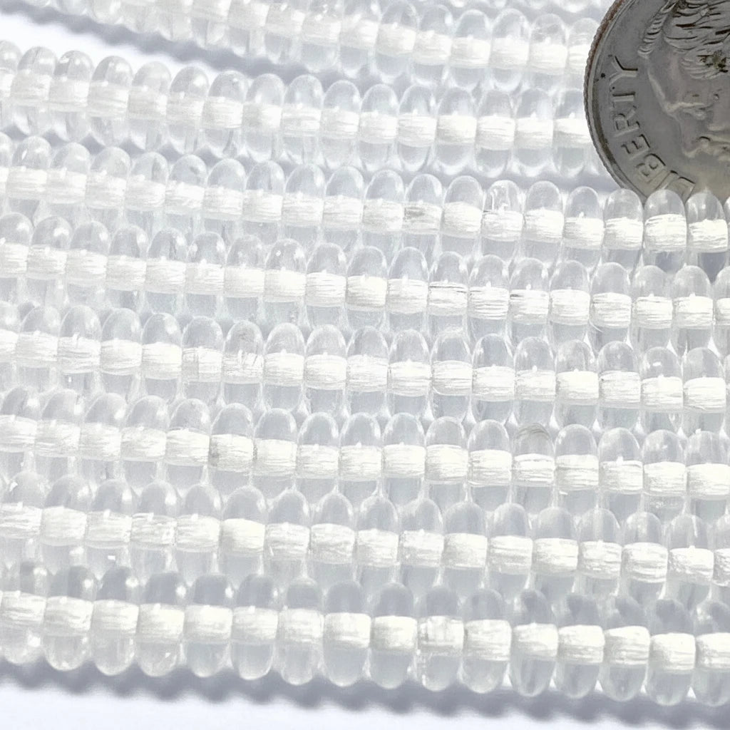 Clear round seed beads strung in multiple rows, with a silver coin in the top right for scale.
