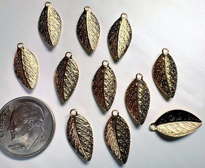 Gold  leaf-shaped pendants on a gray background with a dime for scale.