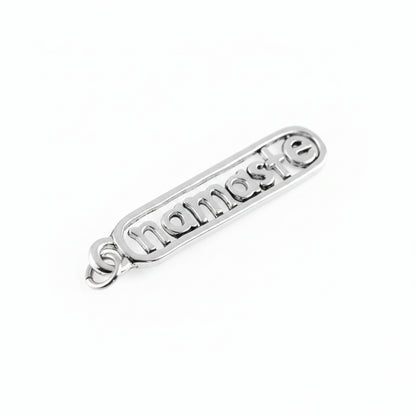 A silver metal charm with the word 'namaste' in raised letters inside an elongated rounded rectangle, with a small loop on the left side, shown on a plain white background.