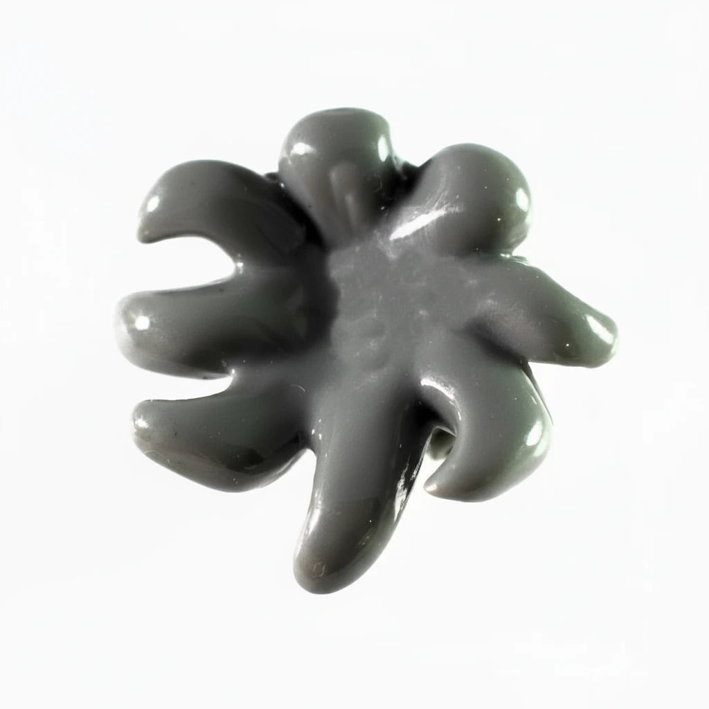 A glossy dark gray stone or resin cabochon with a five-petal, flower-like or starburst shape, shown on a plain white background.