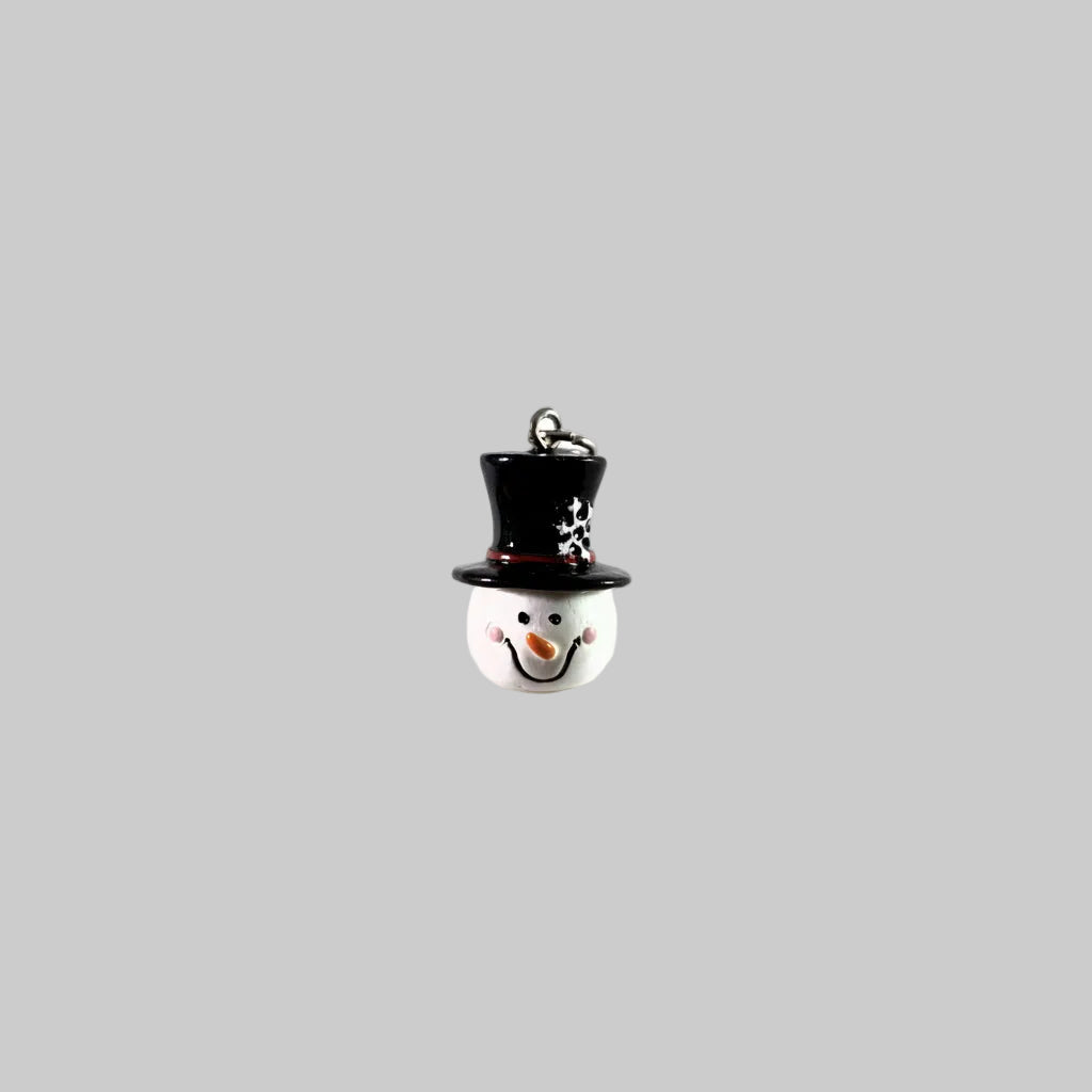 A small snowman ornament or charm with a glossy black top hat, white face and hat base, pink cheeks, an orange carrot nose, and a silver hanging loop at the top, shown on a plain white background.