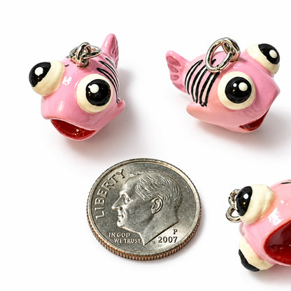 small pink fish-shaped charms with large cartoon eyes and metal key rings, shown on a white background with a coin for scale.
