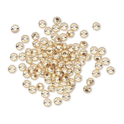 Gold beads scattered on a white background