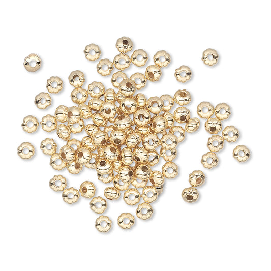 Gold beads scattered on a white background