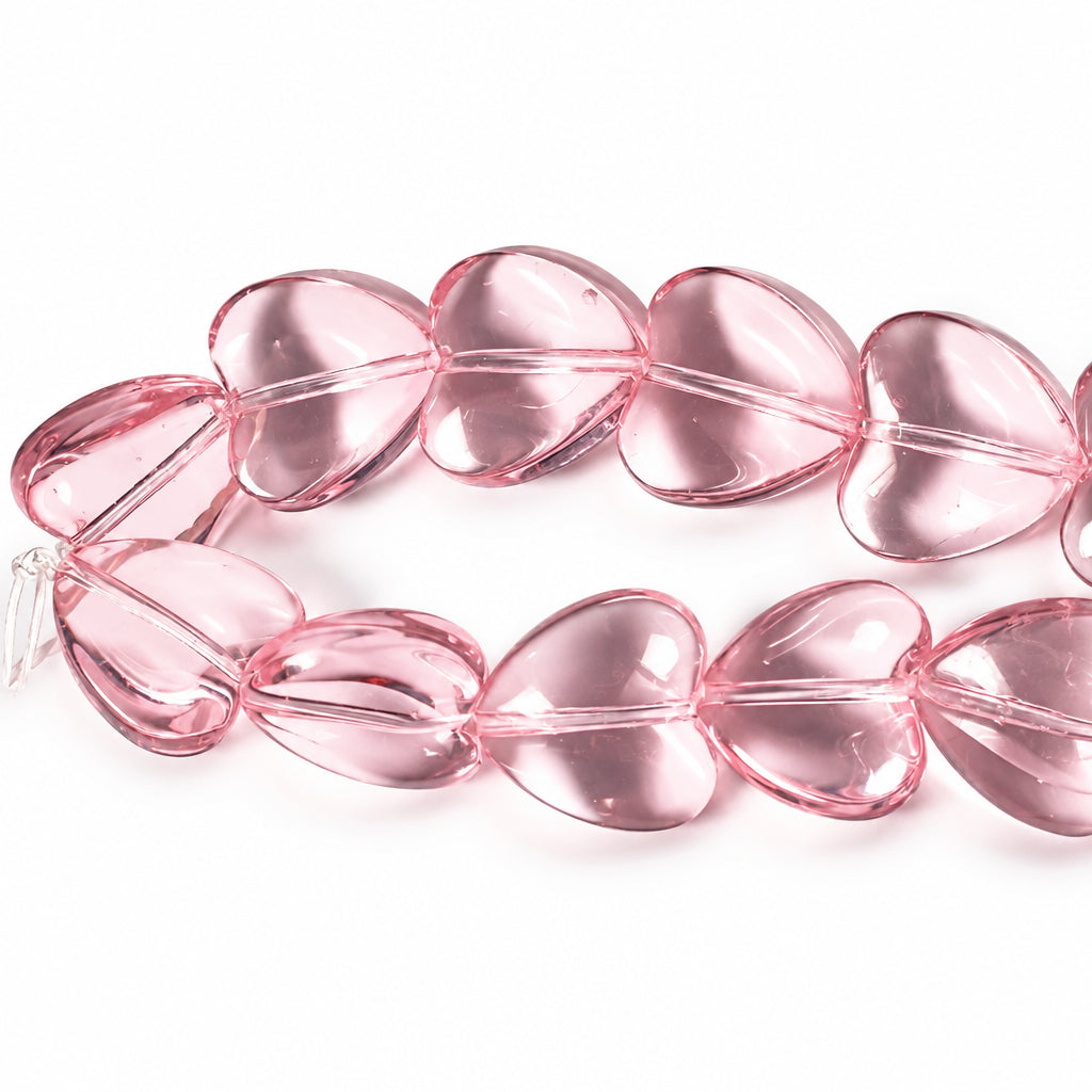 A strand of translucent pink heart-shaped beads on a white background.