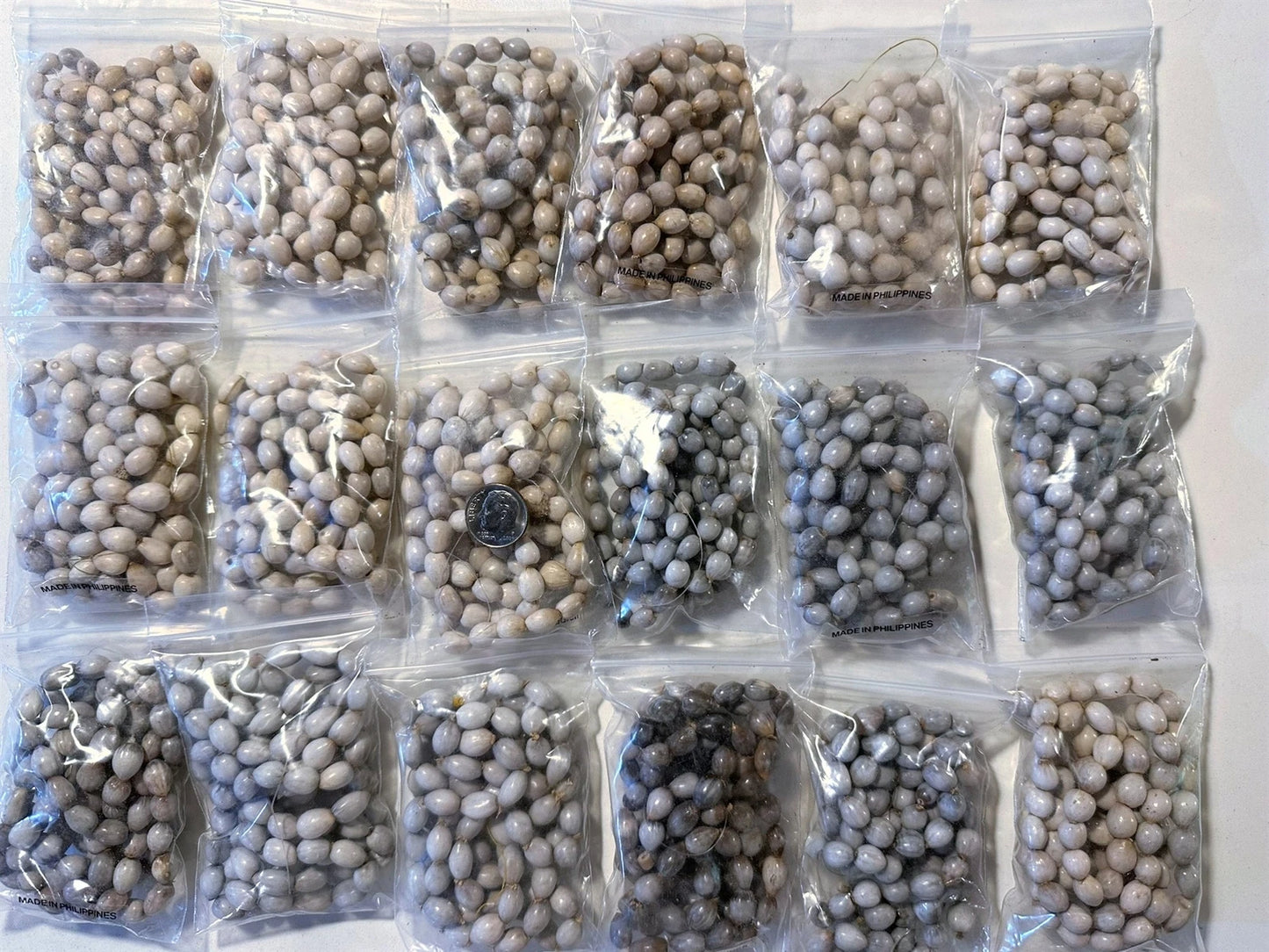 Multiple packages of what appears to be Job's tears beads on a white background