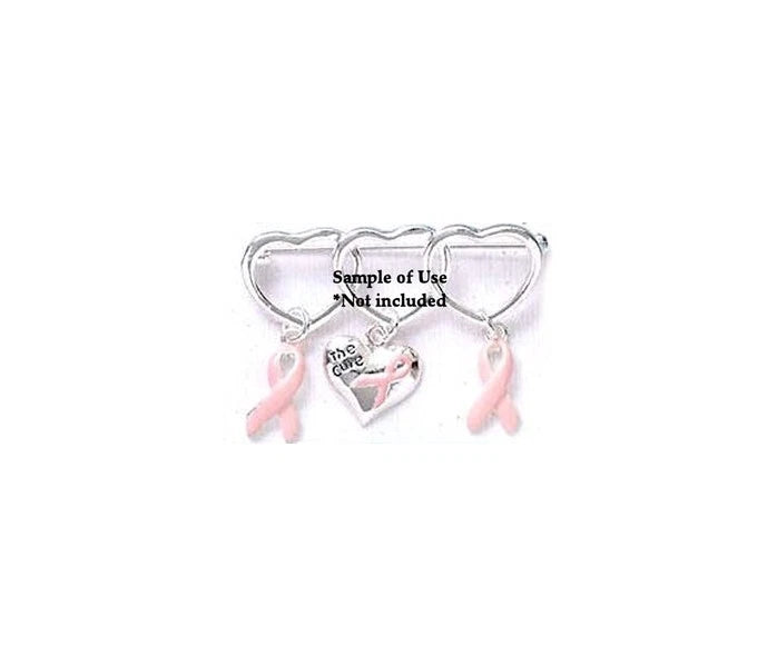 A silver-toned breast cancer awareness pin featuring three interlocking hearts, with two pink ribbon charms and a central heart engraved with 'the care' and a pink ribbon, shown on a plain white background.