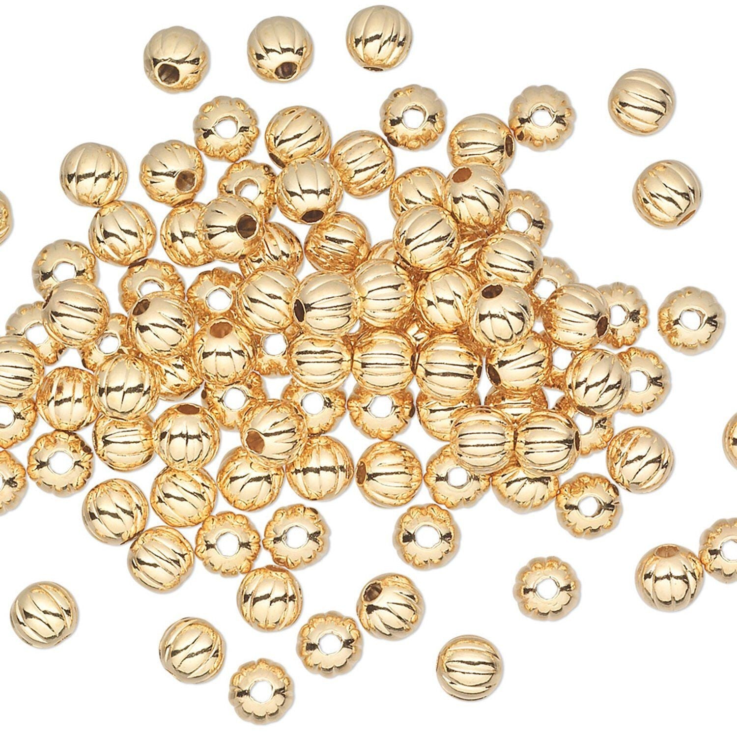A pile of small, shiny gold metallic beads with a ribbed texture and pre-drilled holes, scattered on a plain white background.