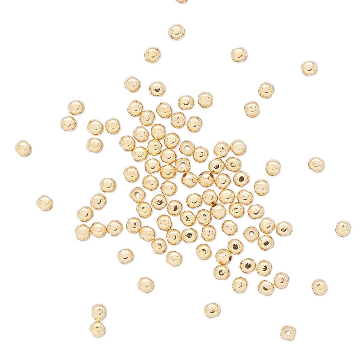 Gold beads scattered on a white background
