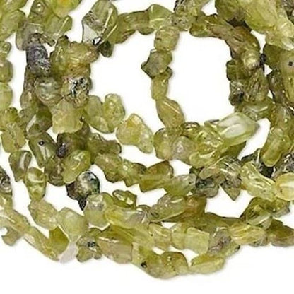 Green rough-cut gemstone beads coiled on a white background.