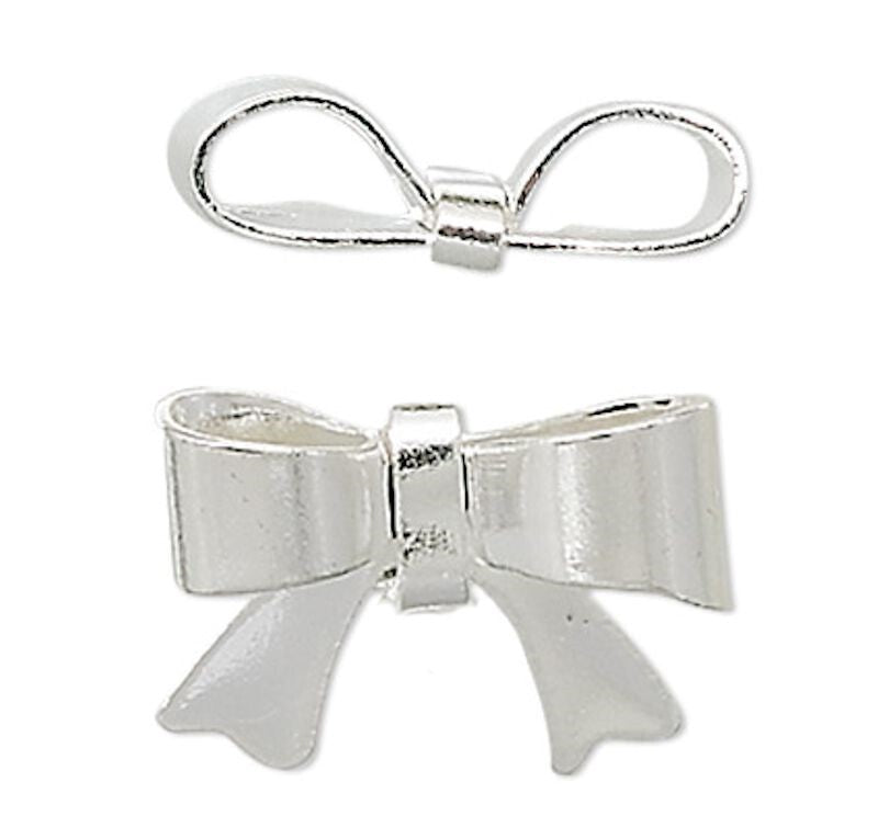 Two silver metal bow charms, one smaller and positioned above, and one larger and positioned below, shown on a plain white background.