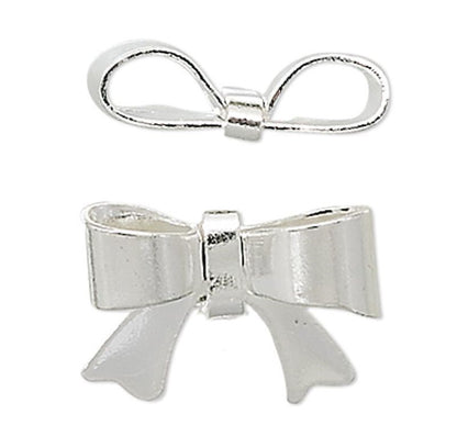 Two silver metal bow charms, one smaller and positioned above, and one larger and positioned below, shown on a plain white background.