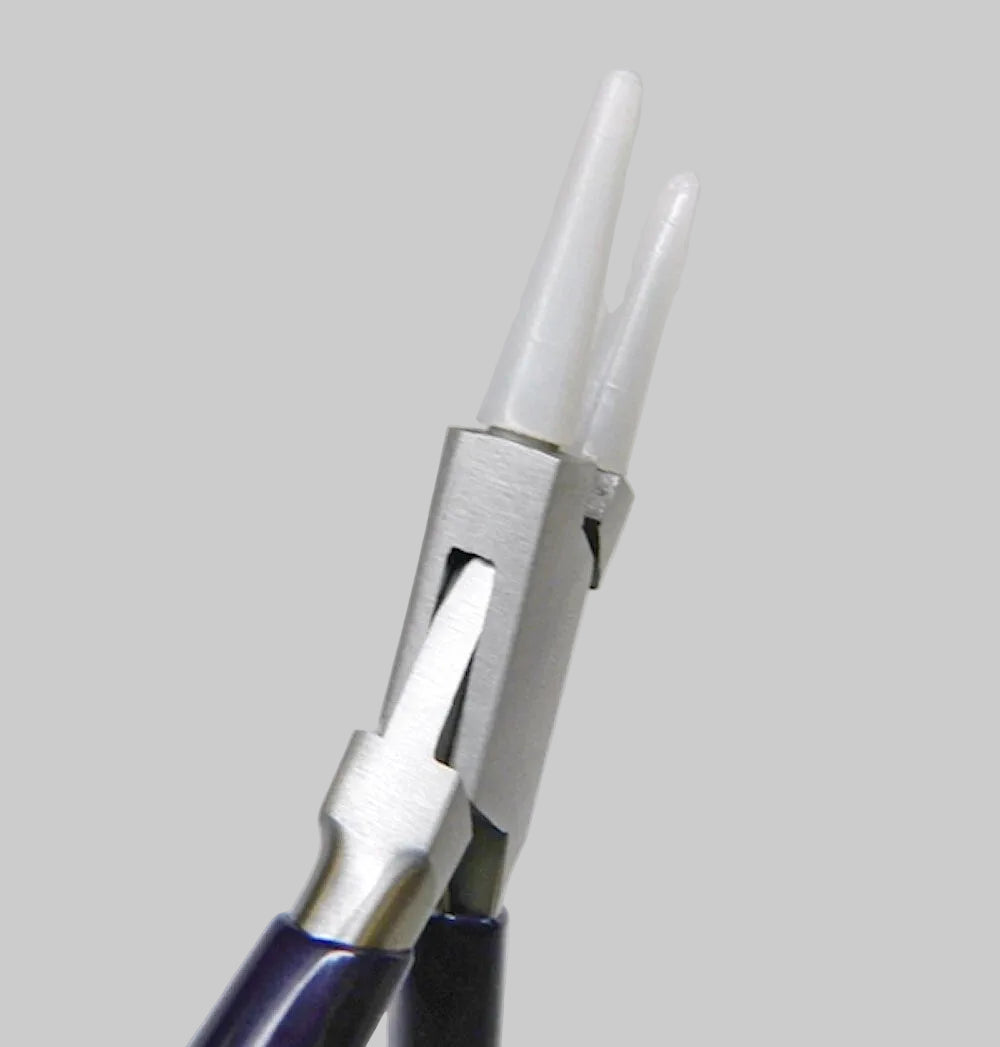 Close-up of a metal ring mandrel or jewelry forming tool with a silver-toned metal head and dark purple handles, holding a translucent white ring blank against a light gray background.