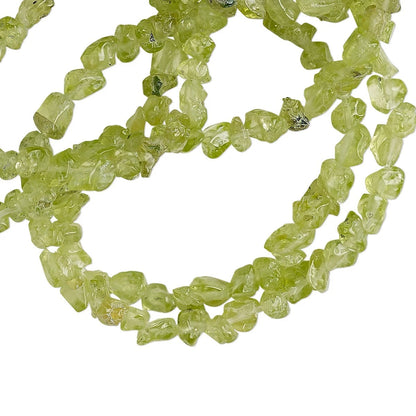 A strand of natural lime green gemstone beads, likely peridot, arranged in loose loops on a solid white background.