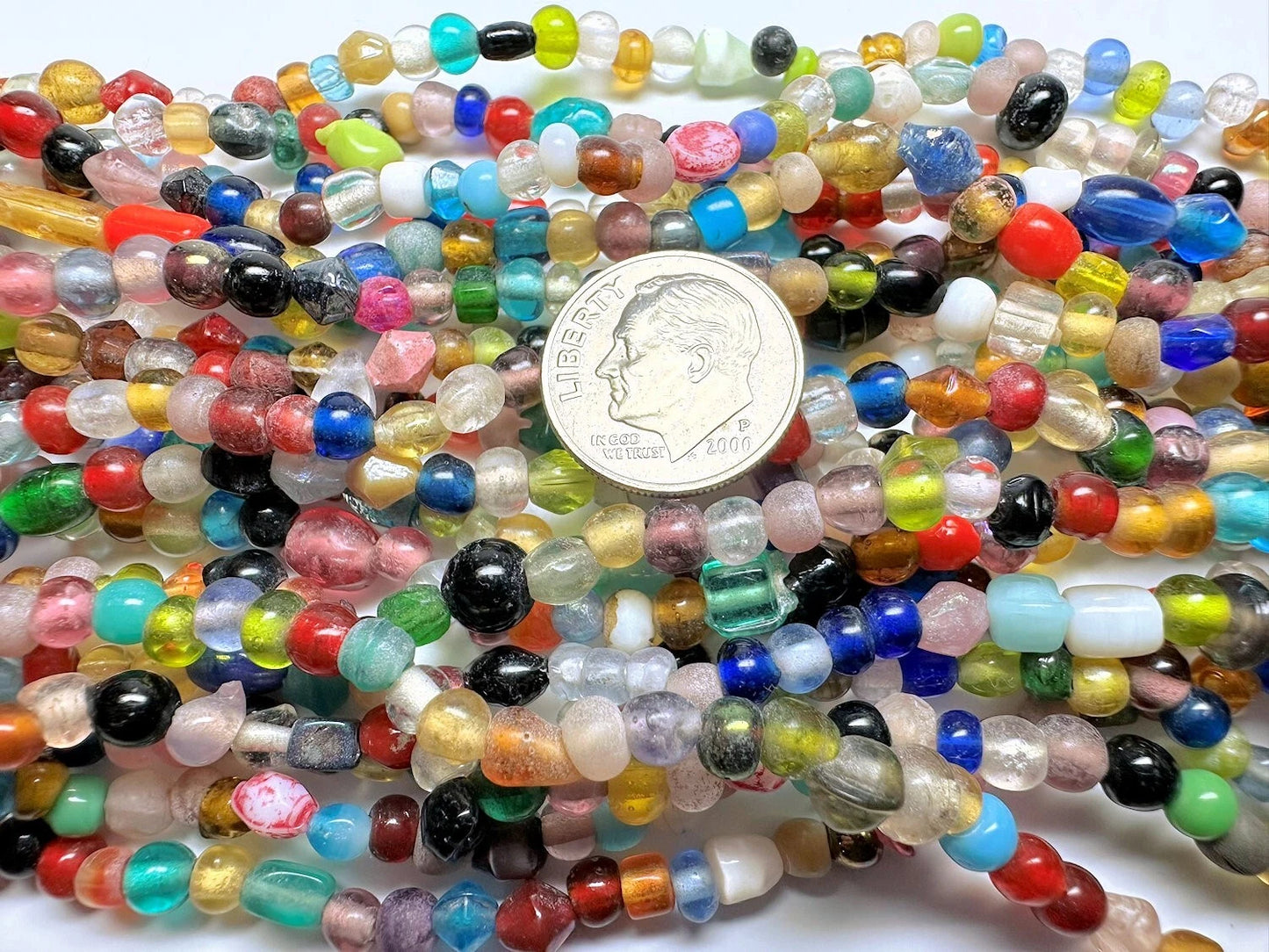 Multicolored beads with a coin for scale on a white background