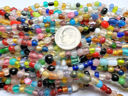 Multicolored beads with a coin for scale on a white background