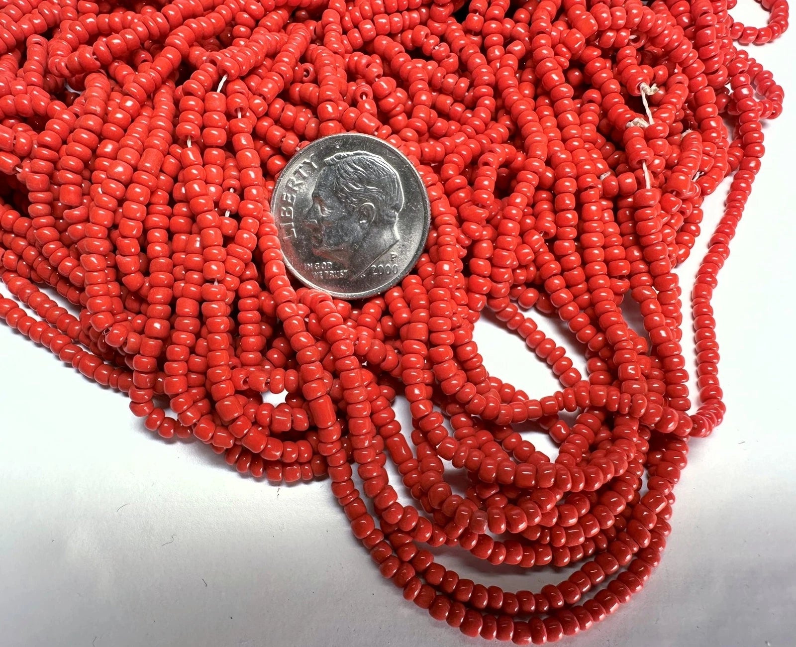 Red beads with a dime for scale on a white background