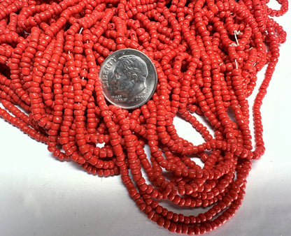 Red beads with a dime for scale on a white background