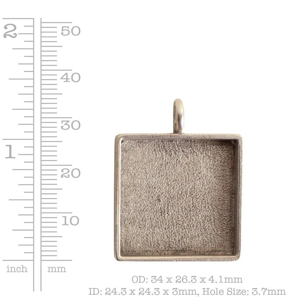 A square metal jewelry setting or pendant blank with a textured interior and top loop, shown next to a ruler scale with measurements in inches and millimeters and text noting OD, ID, and hole size.