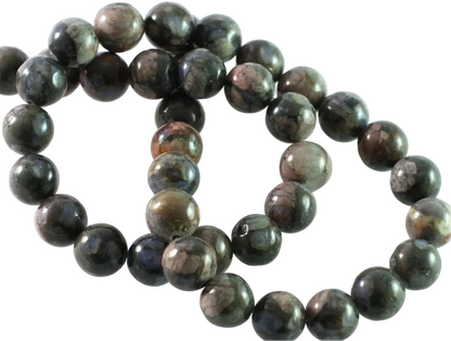 A strand of polished round gemstone beads in dark gray, black, and brown with natural marbled patterns, arranged on a plain white background.