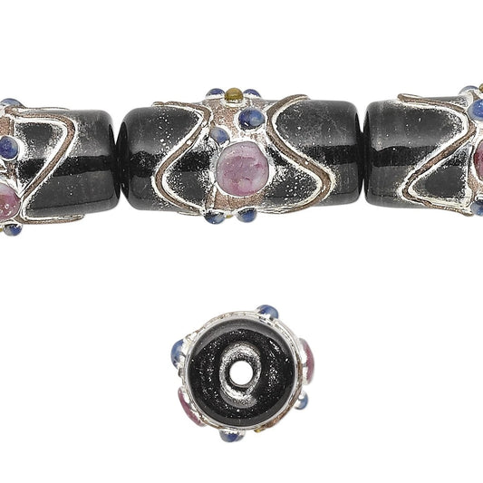 A close-up of decorative glass bead components on a white background, showing a black glass bead with silver filigree and a pink stone, plus a separate circular end piece below.