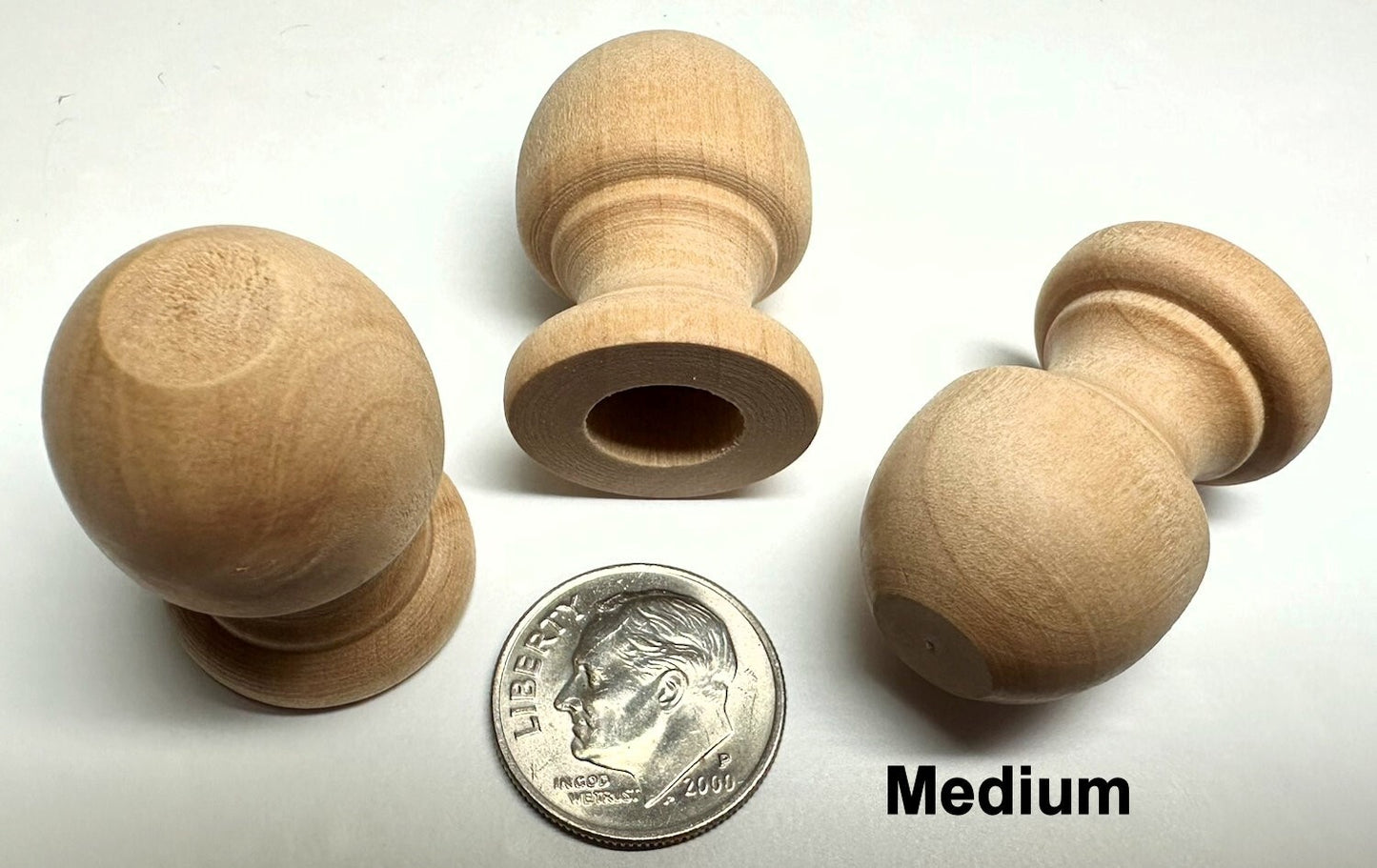 Set of four wooden knobs with a quarter for scale on a white background