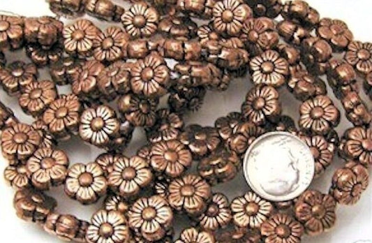 copper floral beads with a dime for scale on a white background