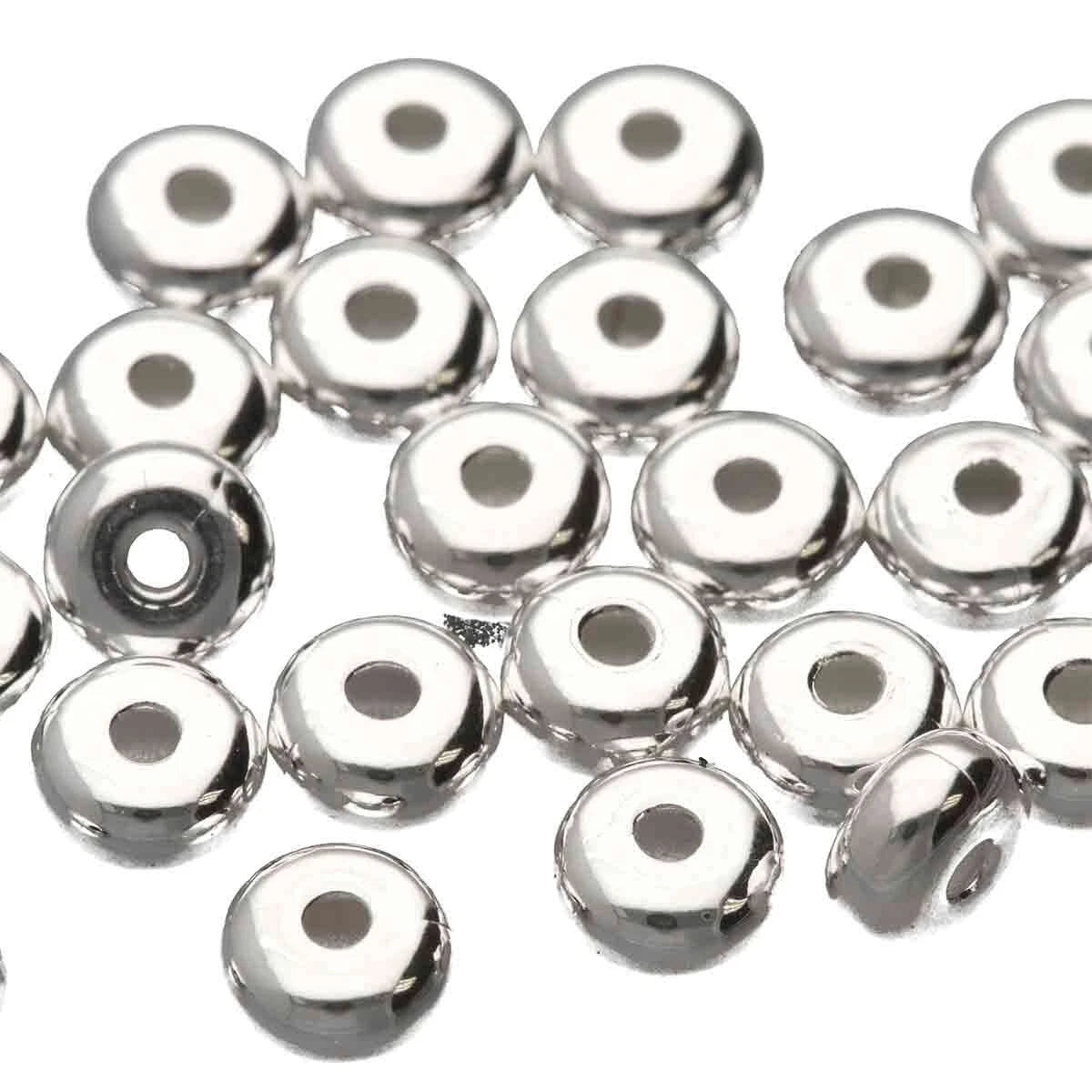 A pile of shiny silver metallic round beads with a central hole, photographed on a plain white background.