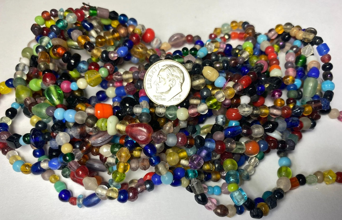 Multicolored beads with a coin for scale on a white background