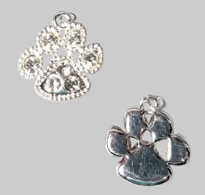 Two silver paw print charms on a light gray background, one embellished with clear rhinestones and the other with a textured metallic finish.