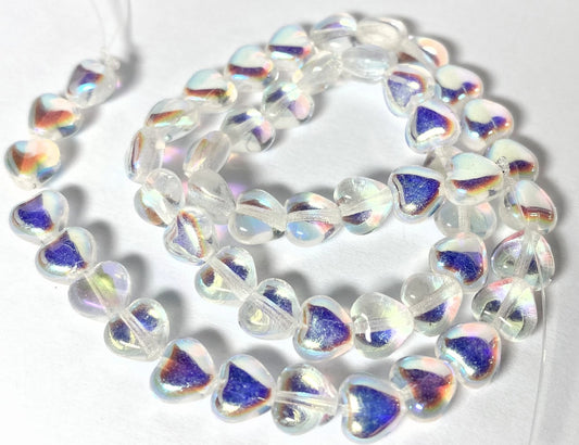 Heart-shaped glass beads with an iridescent white and blue finish, arranged in a loose coil on a white background.