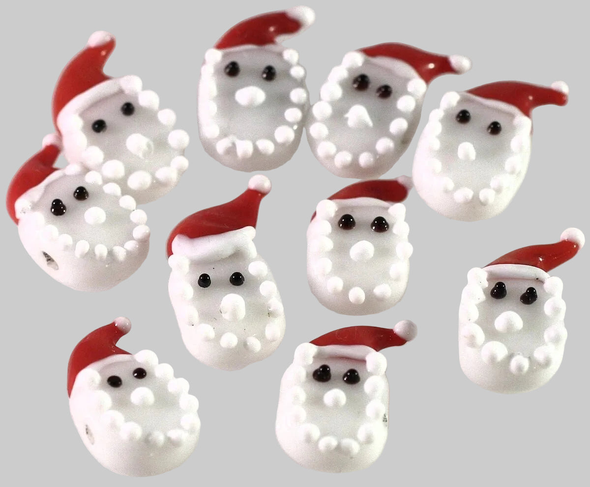 A group of small white Santa Claus face charms with red hats, black eyes, and white beaded outlines, arranged on a plain light background.