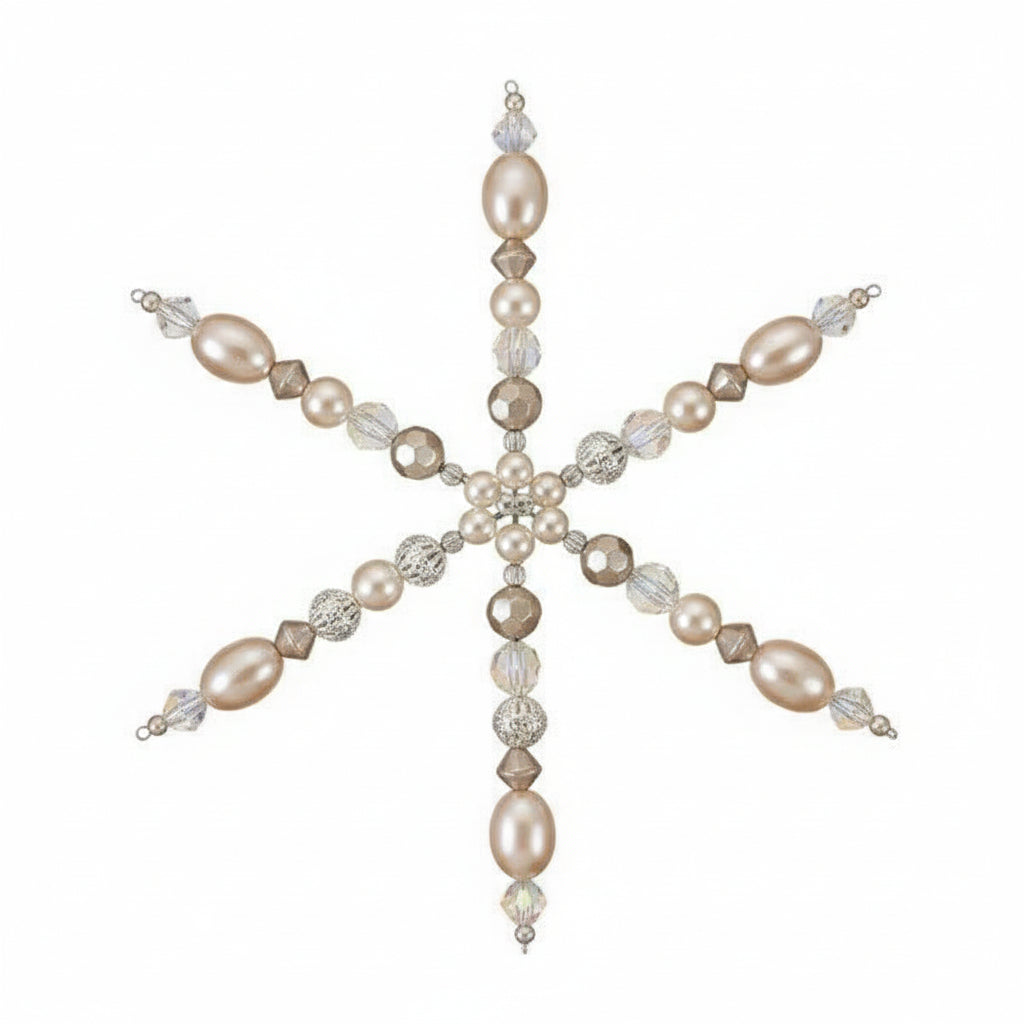 A handmade beaded snowflake ornament held in a person's hand. The ornament features iridescent white pearls, faceted clear beads, and small metallic gold and silver beads, set against a plain light background.